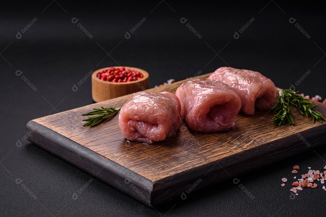 Delicioso rolo de carne de frango ou porco com cogumelos, queijo, especiarias e ervas sobre um fundo escuro de concreto