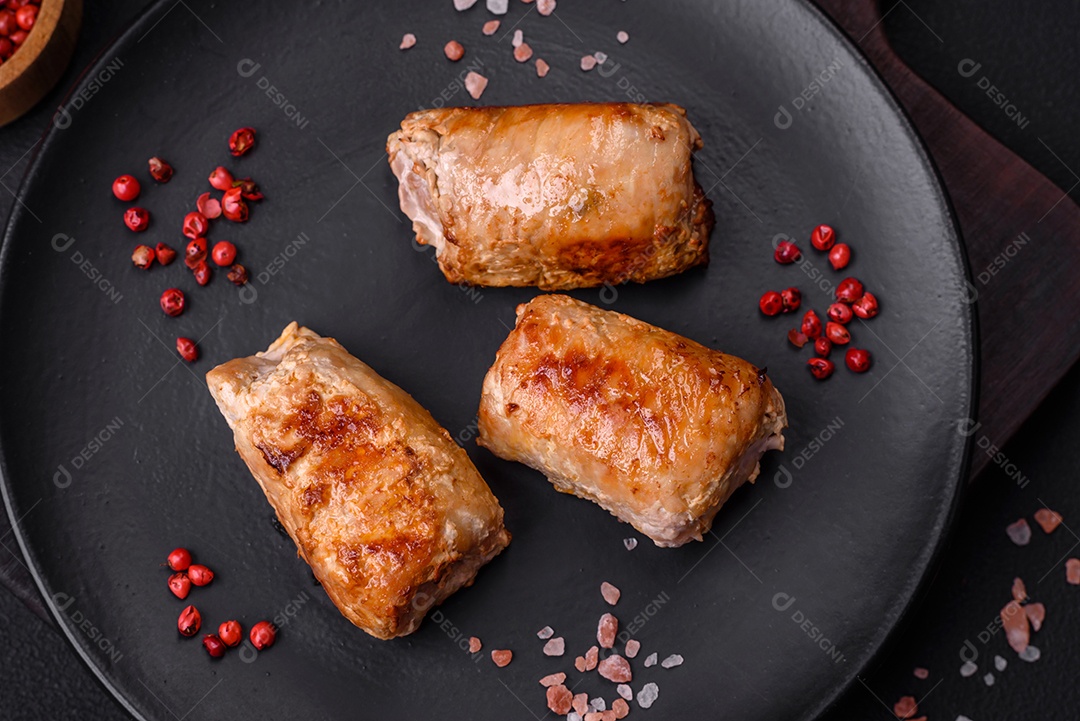 Delicioso rolo de carne de frango ou porco com cogumelos, queijo, especiarias e ervas sobre um fundo escuro de concreto