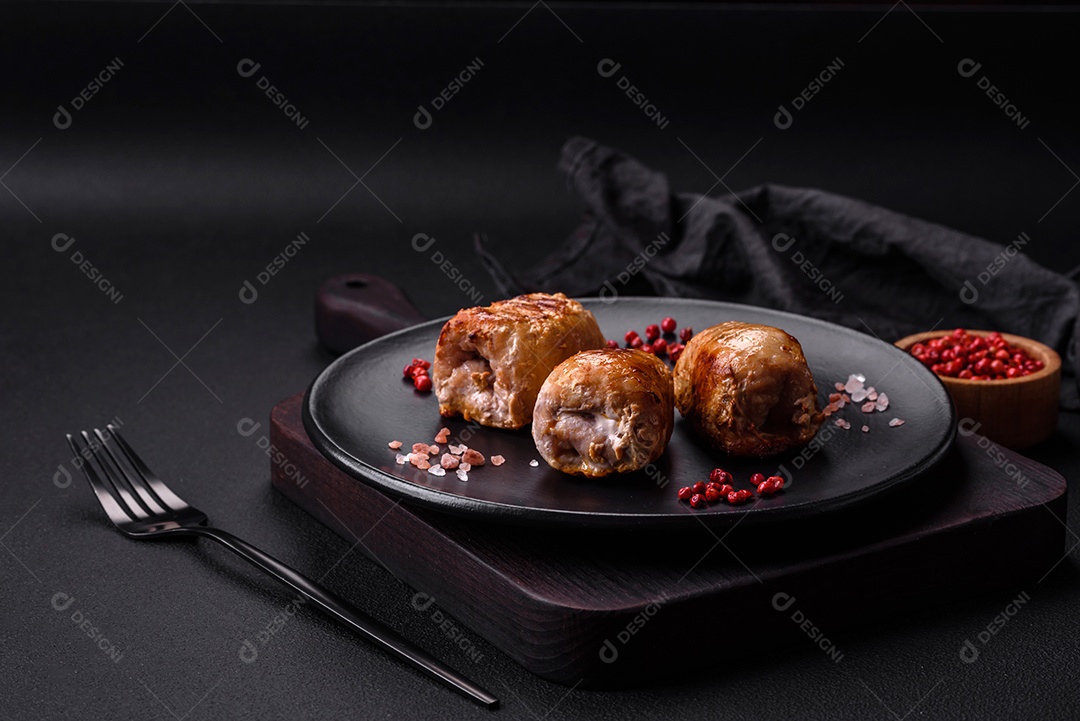 Delicioso rolo de carne de frango ou porco com cogumelos, queijo, especiarias e ervas sobre um fundo escuro de concreto