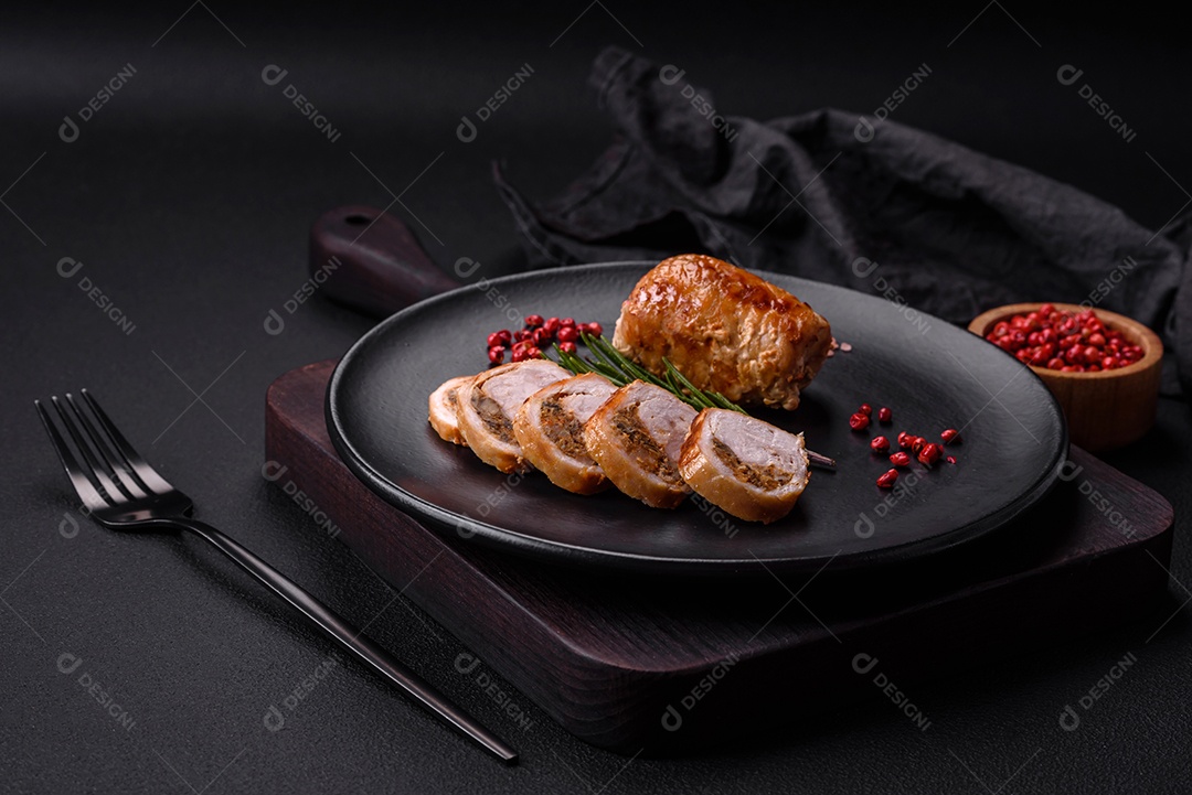 Delicioso rolo de carne de frango ou porco com cogumelos, queijo, especiarias e ervas sobre um fundo escuro de concreto