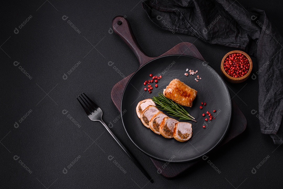 Delicioso rolo de carne de frango ou porco com cogumelos, queijo, especiarias e ervas sobre um fundo escuro de concreto