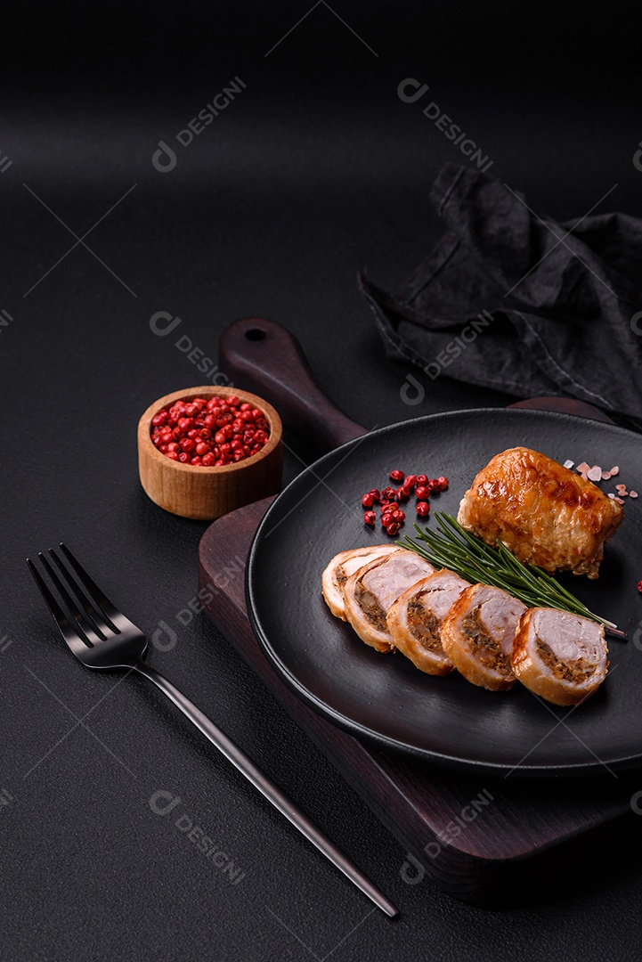 Delicioso rolo de carne de frango ou porco com cogumelos, queijo, especiarias e ervas sobre um fundo escuro de concreto