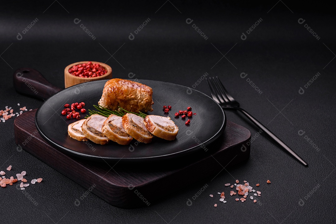 Delicioso rolo de carne de frango ou porco com cogumelos, queijo, especiarias e ervas sobre um fundo escuro de concreto