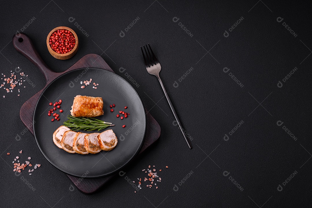 Delicioso rolo de carne de frango ou porco com cogumelos, queijo, especiarias e ervas sobre um fundo escuro de concreto