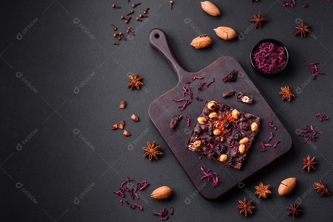 Chocolate artesanal com frutas, nozes e especiarias em um fundo escuro de concreto. Doces feitos em casa