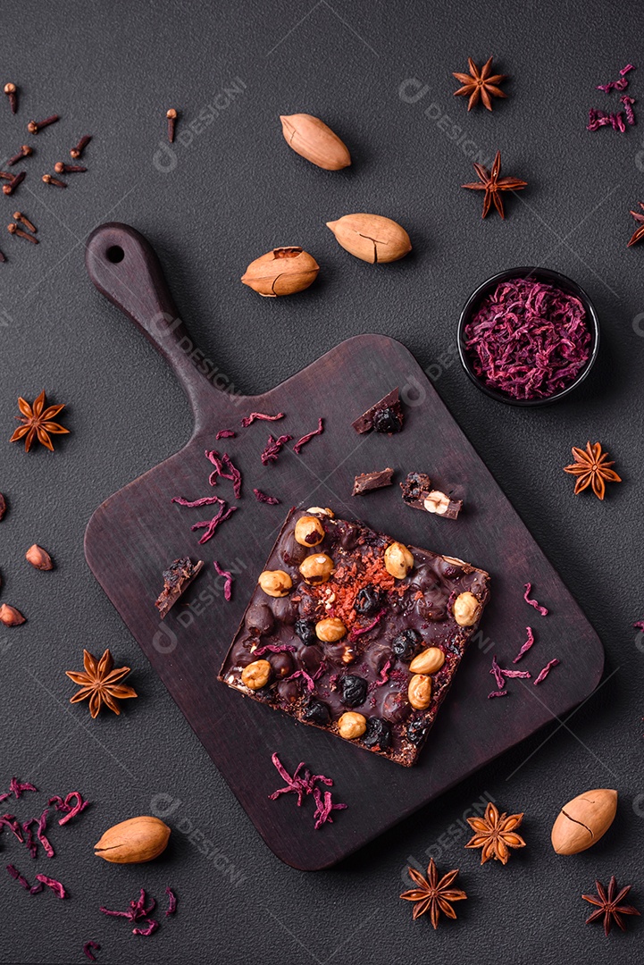 Chocolate artesanal com frutas, nozes e especiarias em um fundo escuro de concreto. Doces feitos em casa