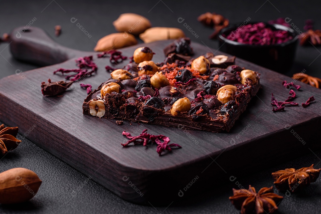 Chocolate artesanal com frutas, nozes e especiarias em um fundo escuro de concreto. Doces feitos em casa