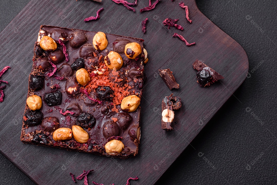 Chocolate artesanal com frutas, nozes e especiarias em um fundo escuro de concreto. Doces feitos em casa