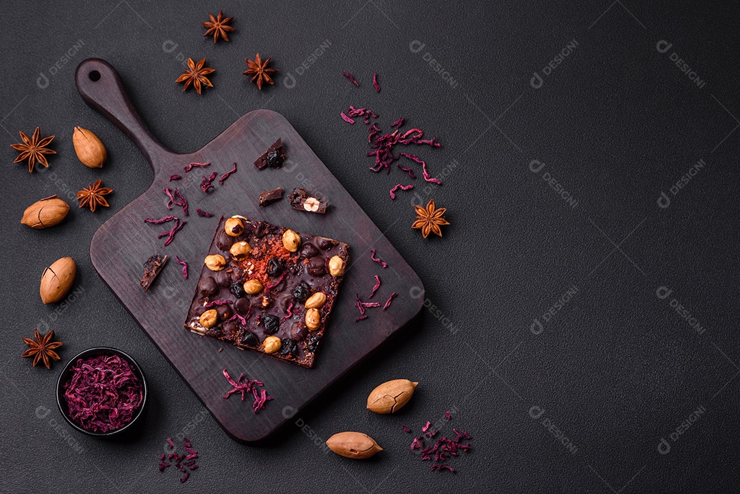 Chocolate artesanal com frutas, nozes e especiarias em um fundo escuro de concreto. Doces feitos em casa