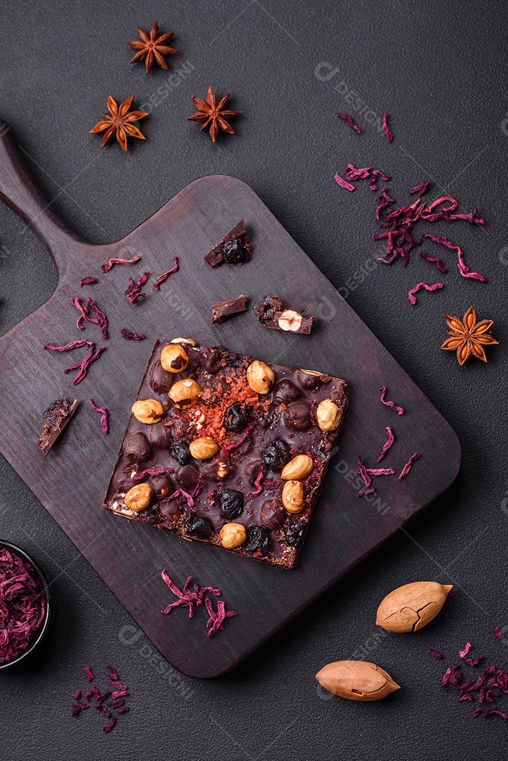 Chocolate artesanal com frutas, nozes e especiarias em um fundo escuro de concreto. Doces feitos em casa