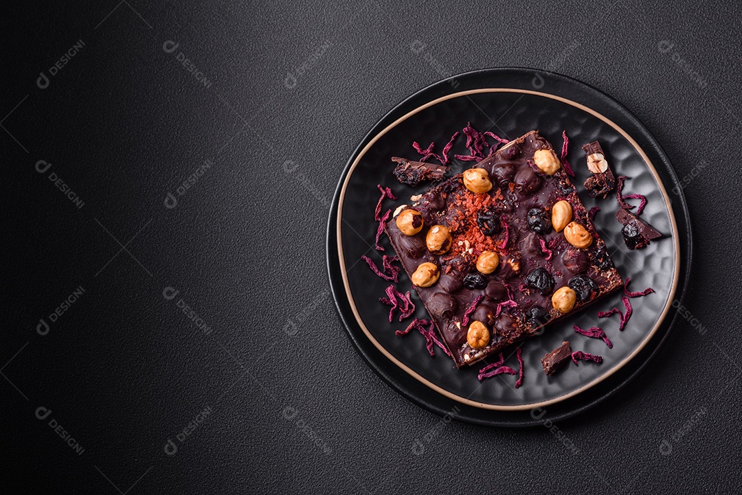 Chocolate artesanal com frutas, nozes e especiarias em um fundo escuro de concreto. Doces feitos em casa