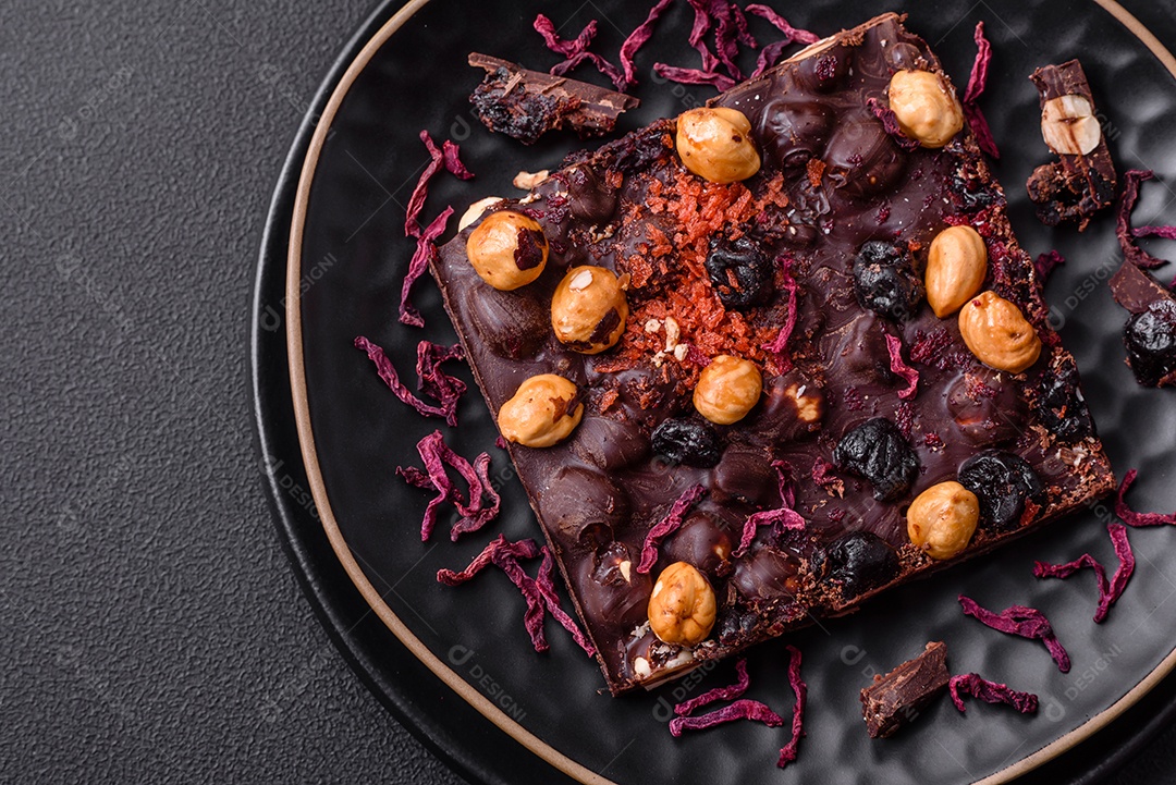 Chocolate artesanal com frutas, nozes e especiarias em um fundo escuro de concreto. Doces feitos em casa