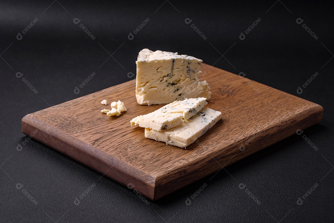 Delicioso queijo fresco com molde azul dorblu sobre uma tábua de madeira sobre um fundo escuro de concreto