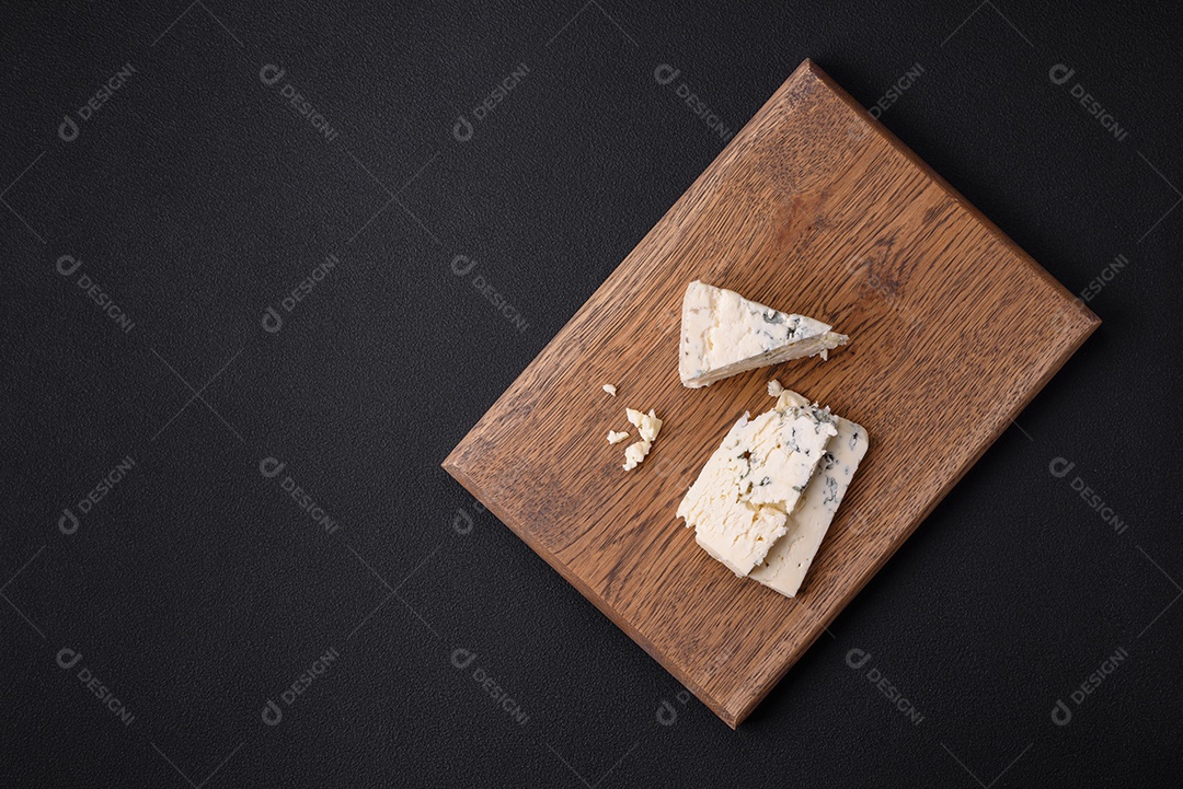 Delicioso queijo fresco com molde azul dorblu sobre uma tábua de madeira sobre um fundo escuro de concreto