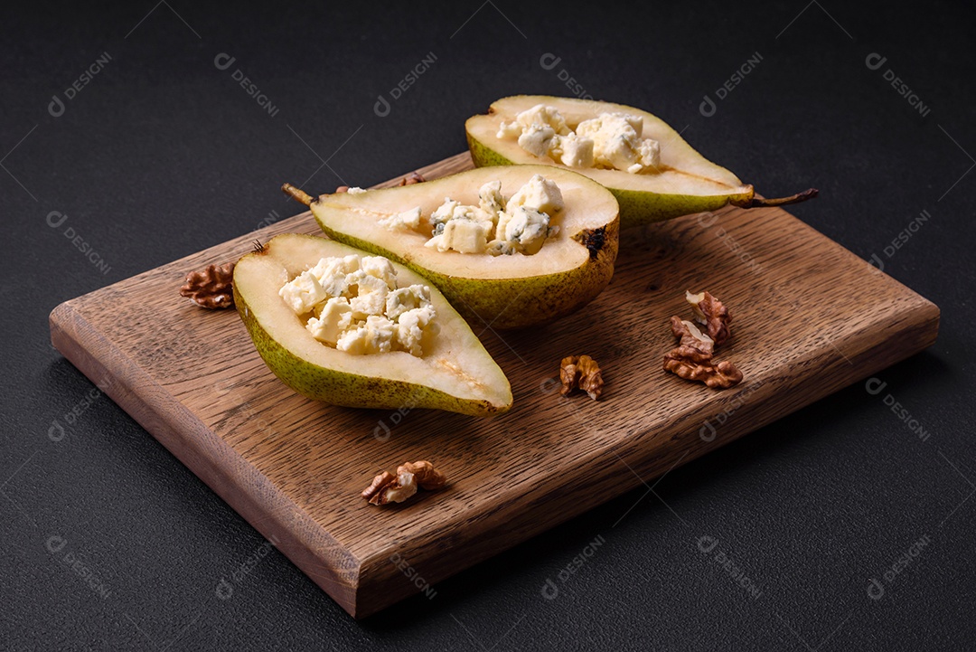 Deliciosa pêra assada com queijo dorblu, nozes e mel sobre um fundo de concreto texturizado. Prato vegetariano
