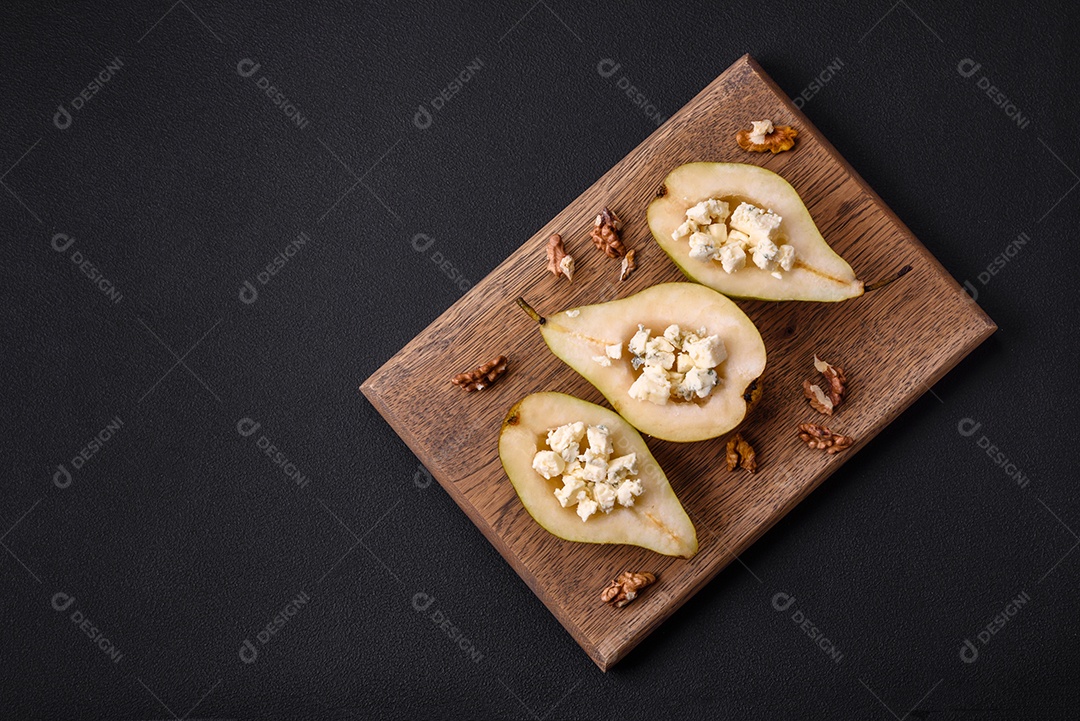 Deliciosa pêra assada com queijo dorblu, nozes e mel sobre um fundo de concreto texturizado. Prato vegetariano