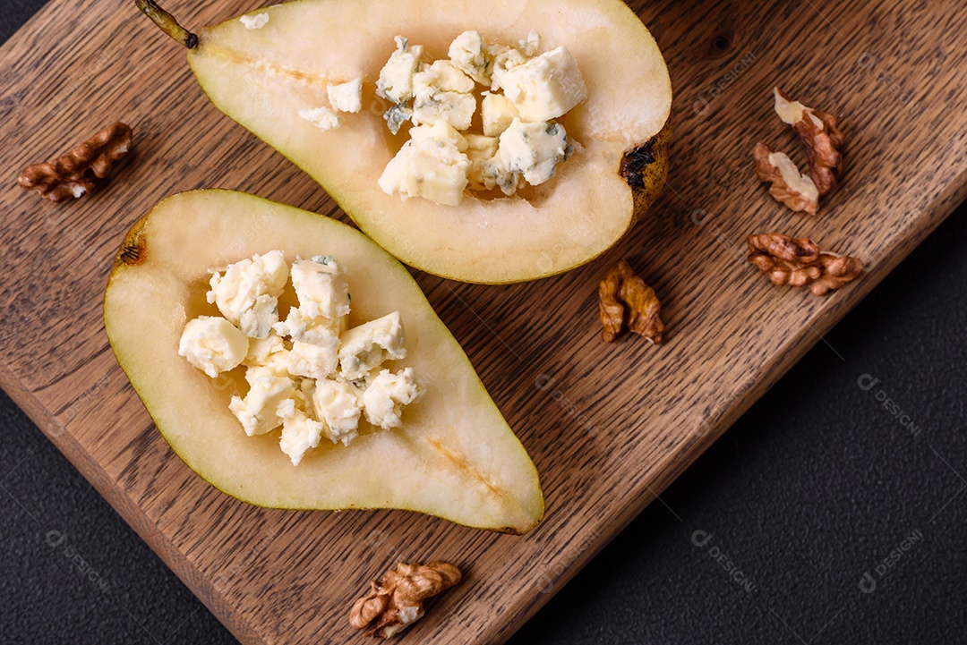 Deliciosa pêra assada com queijo dorblu, nozes e mel sobre um fundo de concreto texturizado. Prato vegetariano