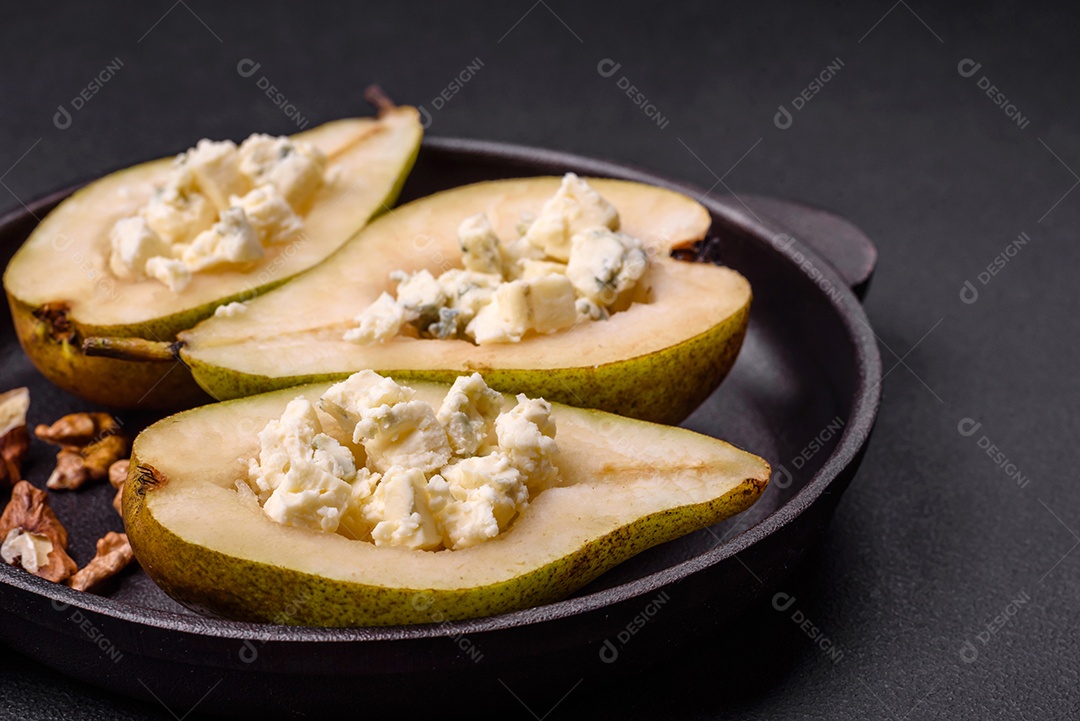 Deliciosa pêra assada com queijo dorblu, nozes e mel sobre um fundo de concreto texturizado. Prato vegetariano