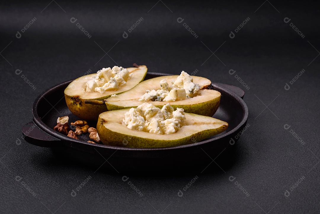 Deliciosa pêra assada com queijo dorblu, nozes e mel sobre um fundo de concreto texturizado. Prato vegetariano