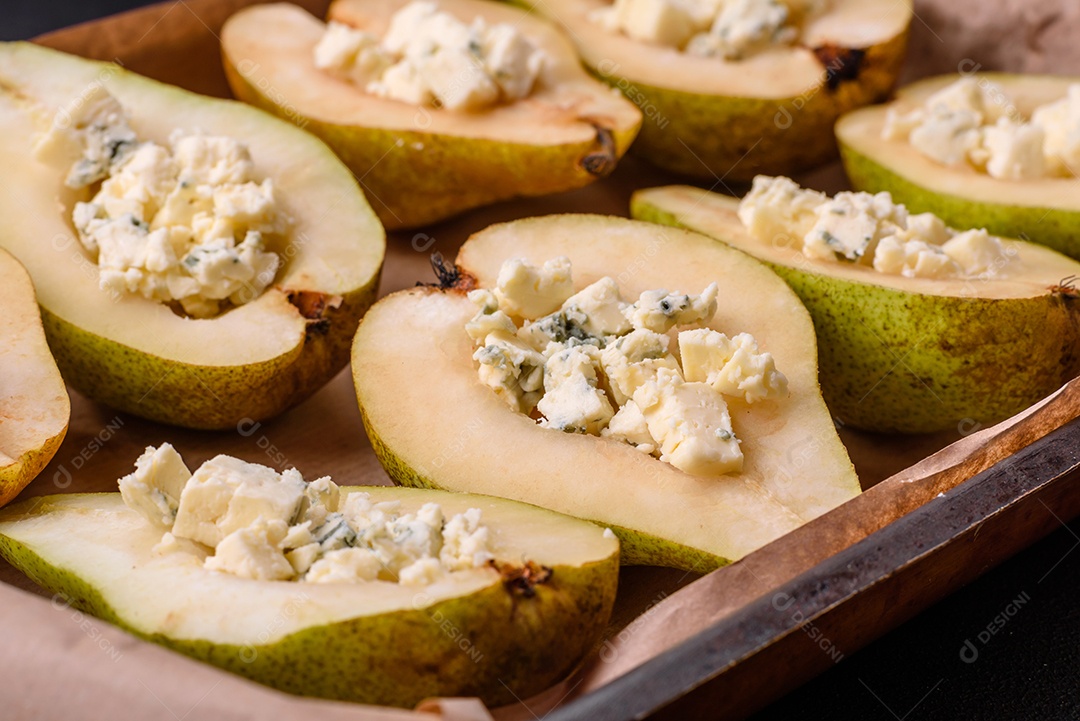 Deliciosa pêra assada com queijo dorblu, nozes e mel sobre um fundo de concreto texturizado. Prato vegetariano