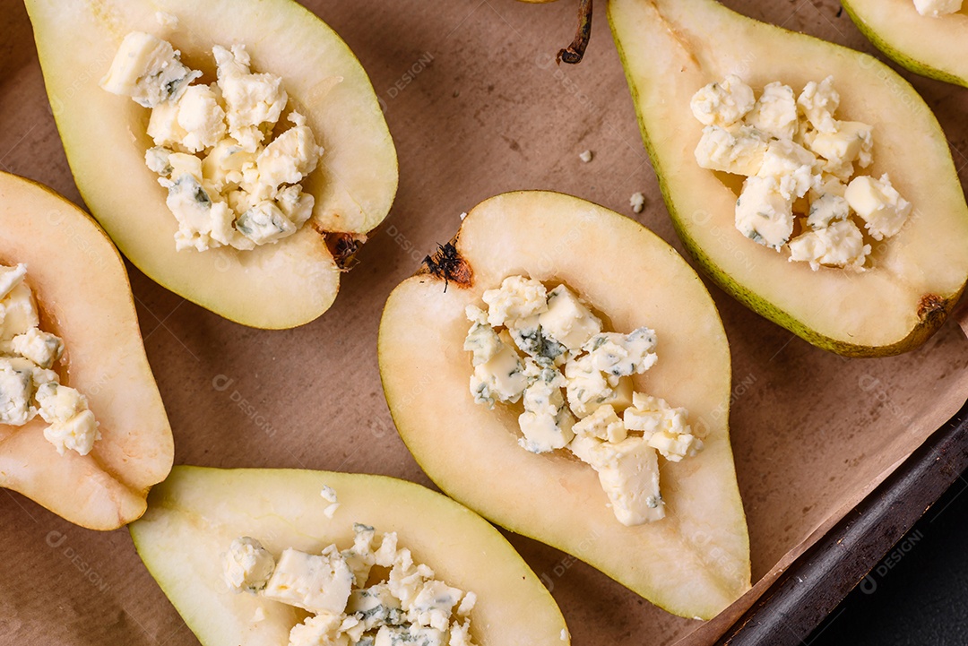 Deliciosa pêra assada com queijo dorblu, nozes e mel sobre um fundo de concreto texturizado. Prato vegetariano