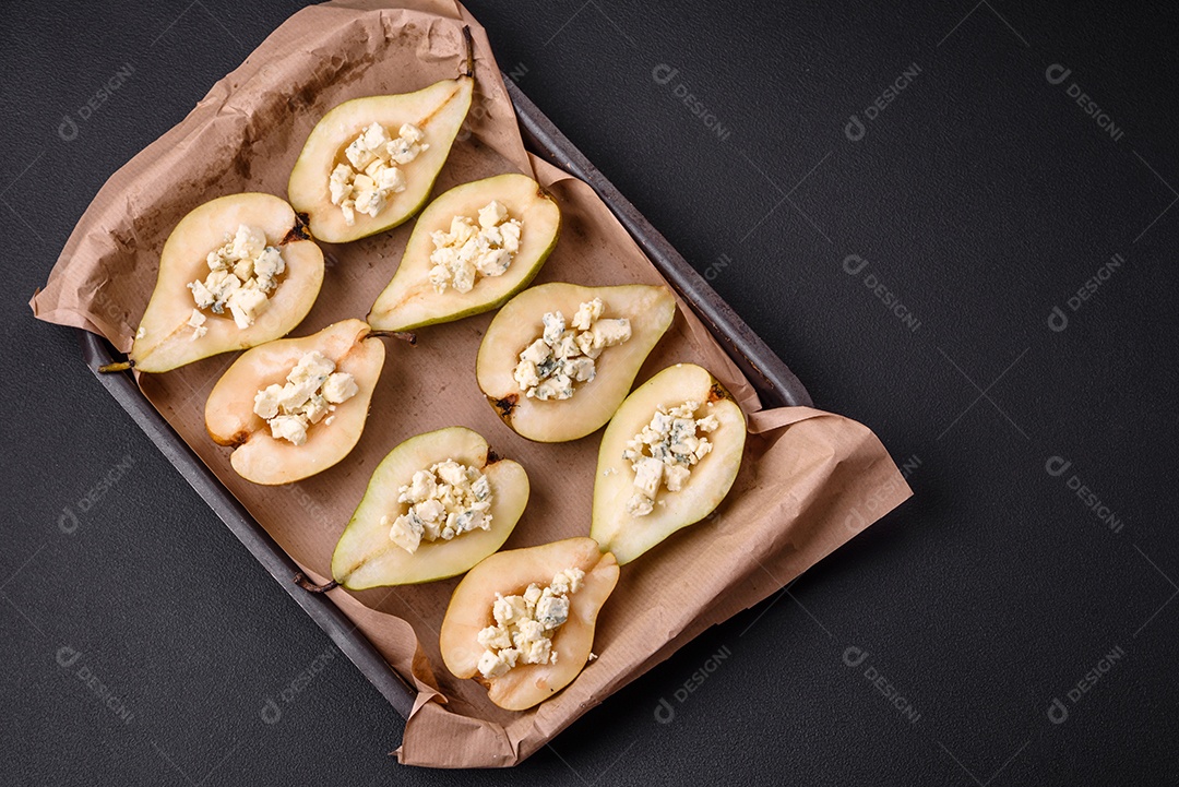 Deliciosa pêra assada com queijo dorblu, nozes e mel sobre um fundo de concreto texturizado. Prato vegetariano