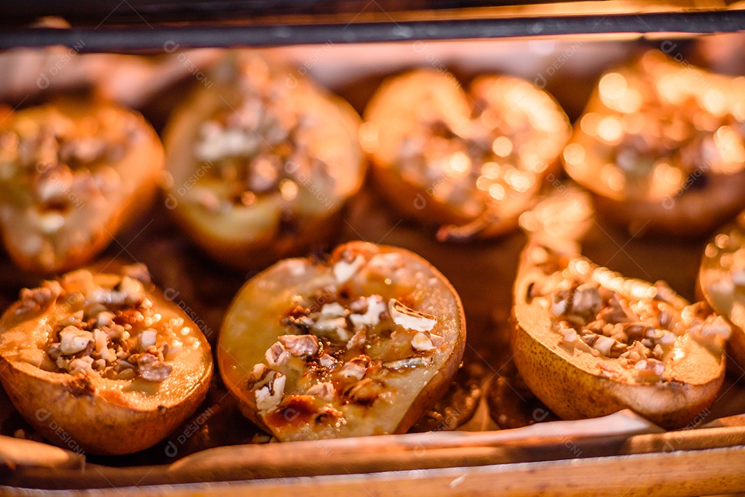 Deliciosa pêra assada com queijo dorblu, nozes e mel sobre um fundo de concreto texturizado. Prato vegetariano