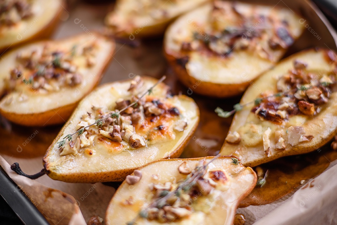 Deliciosa pêra assada com queijo dorblu, nozes e mel sobre um fundo de concreto texturizado. Prato vegetariano