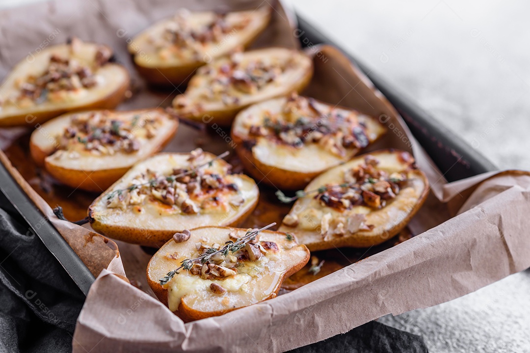 Deliciosa pêra assada com queijo dorblu, nozes e mel sobre um fundo de concreto texturizado. Prato vegetariano