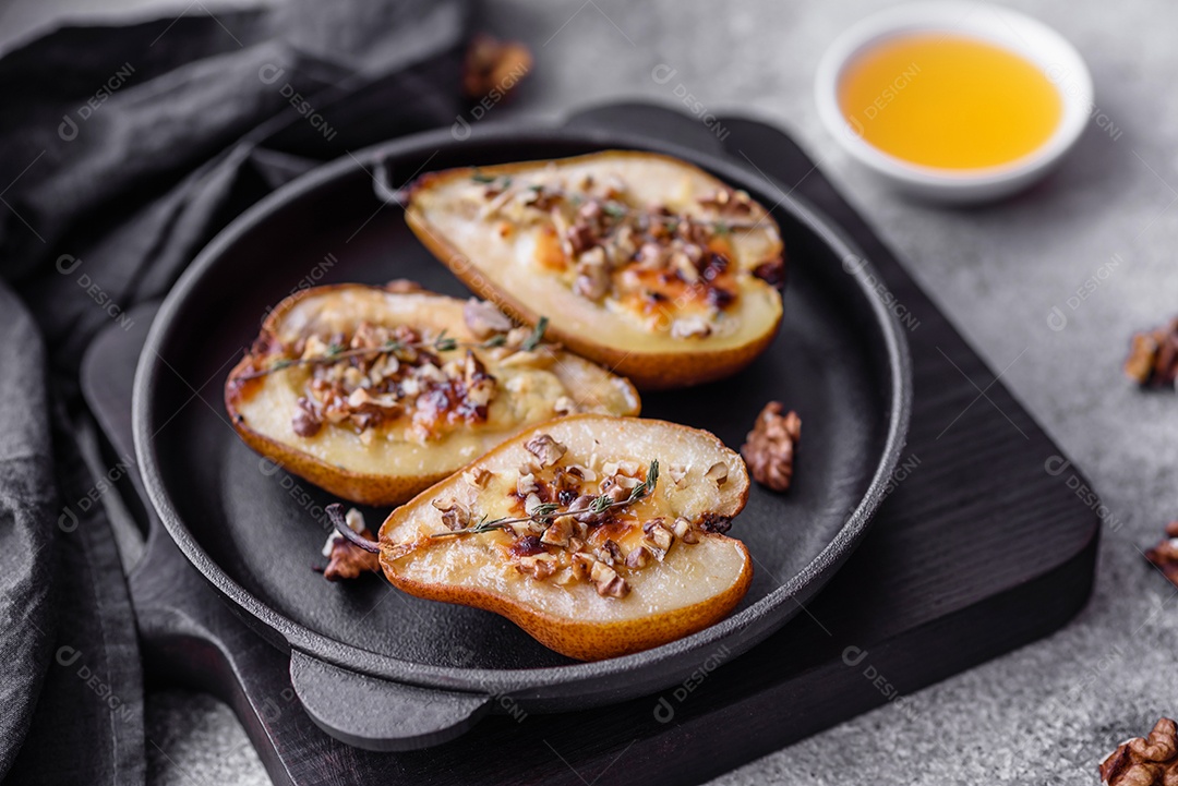 Deliciosa pêra assada com queijo dorblu, nozes e mel sobre um fundo de concreto texturizado. Prato vegetariano