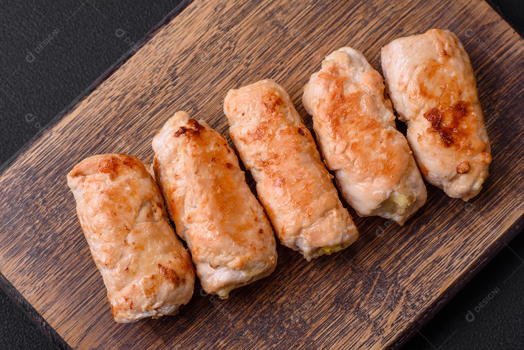 Delicioso rolo de porco ou frango assado com cogumelos, especiarias e ervas dentro sobre um fundo escuro de concreto