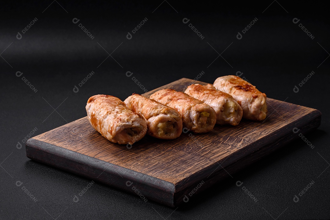 Delicioso rolo de porco ou frango assado com cogumelos, especiarias e ervas dentro sobre um fundo escuro de concreto