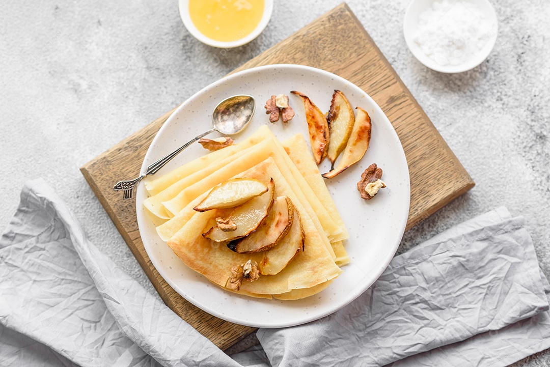Deliciosas panquecas frescas com mel e frutas em um fundo de concreto texturizado. Comida saudável e útil