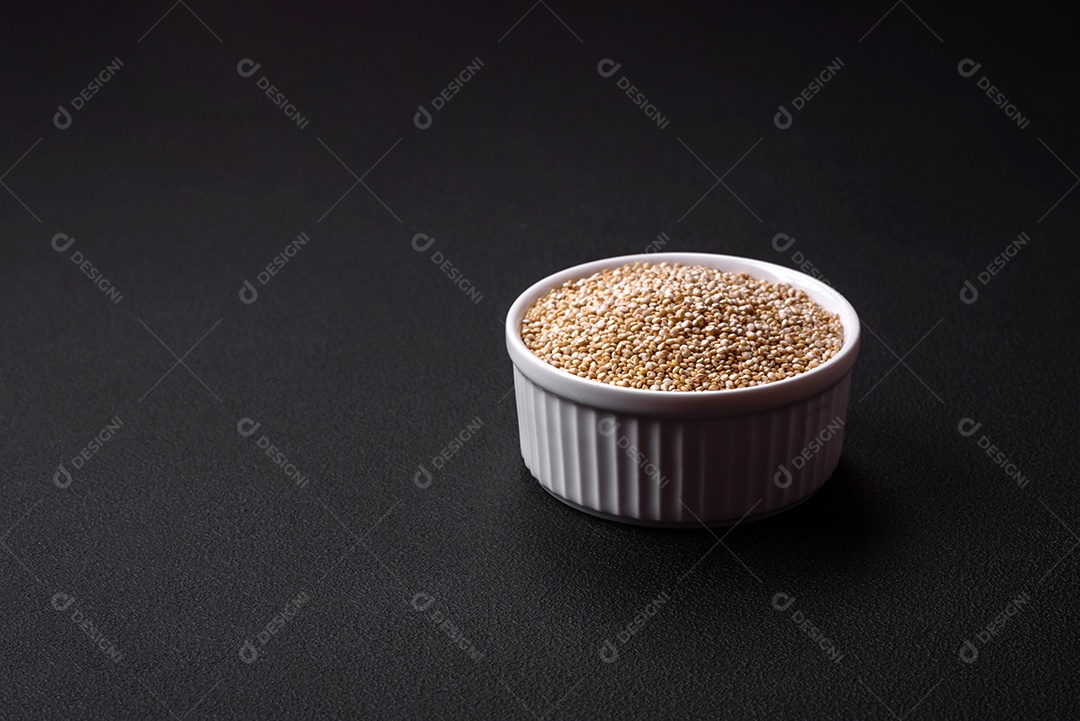Quinoa crua saudável em uma tigela sobre um fundo escuro de concreto. Comida saudável e útil