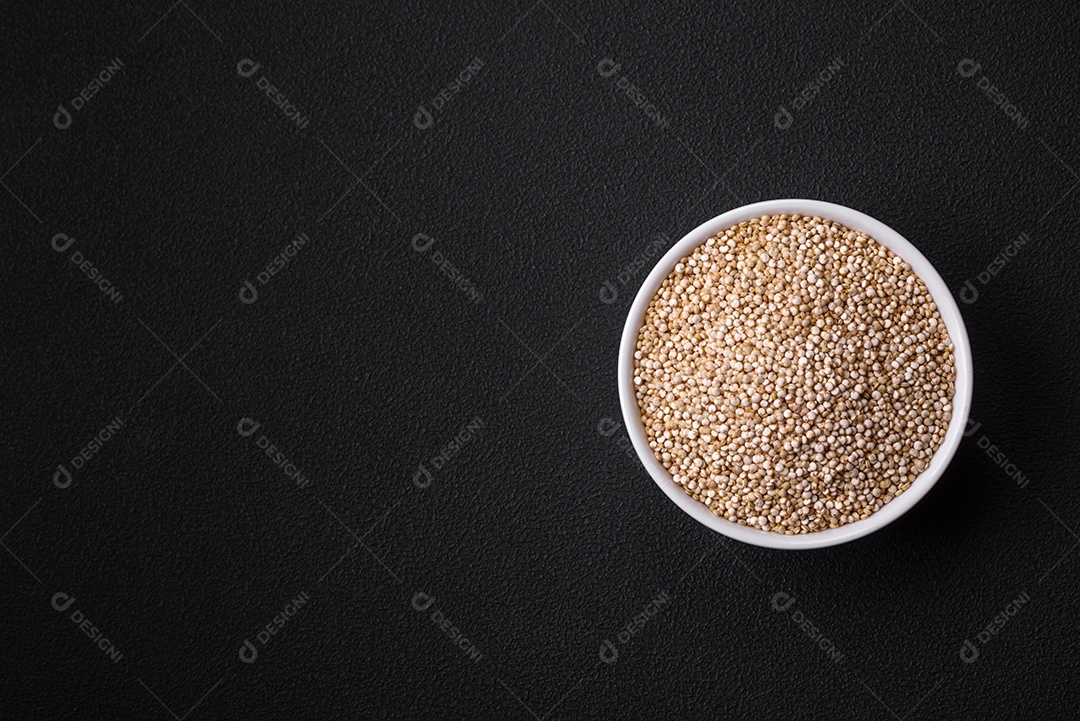 Quinoa crua saudável em uma tigela sobre um fundo escuro de concreto. Comida saudável e útil