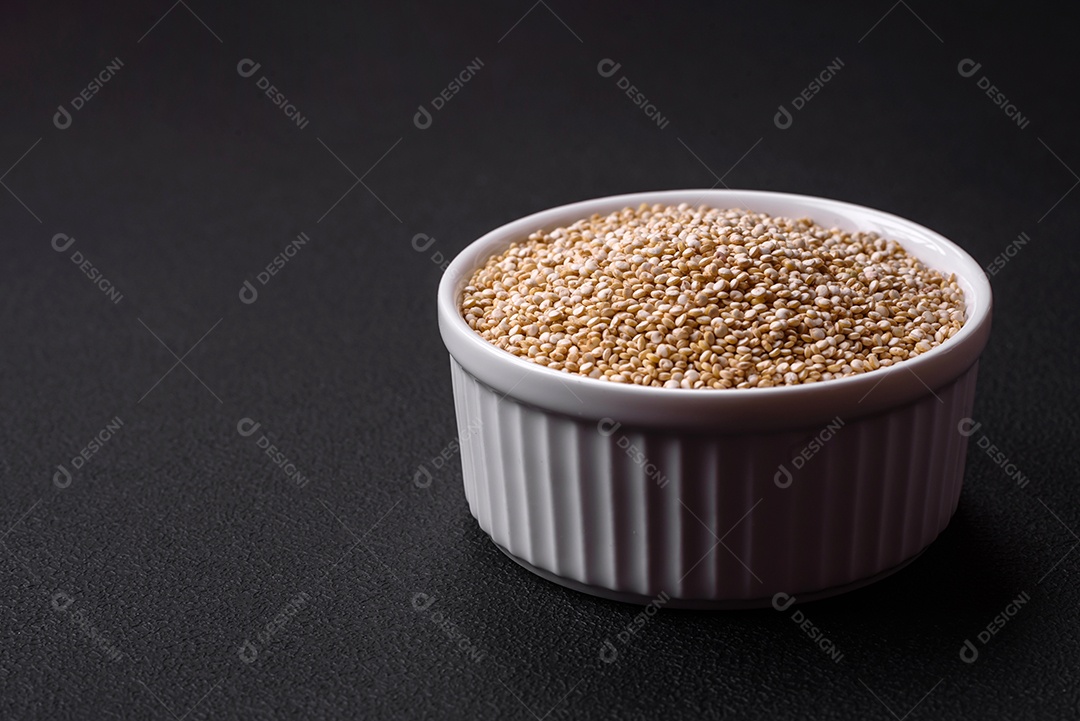Quinoa crua saudável em uma tigela sobre um fundo escuro de concreto. Comida saudável e útil