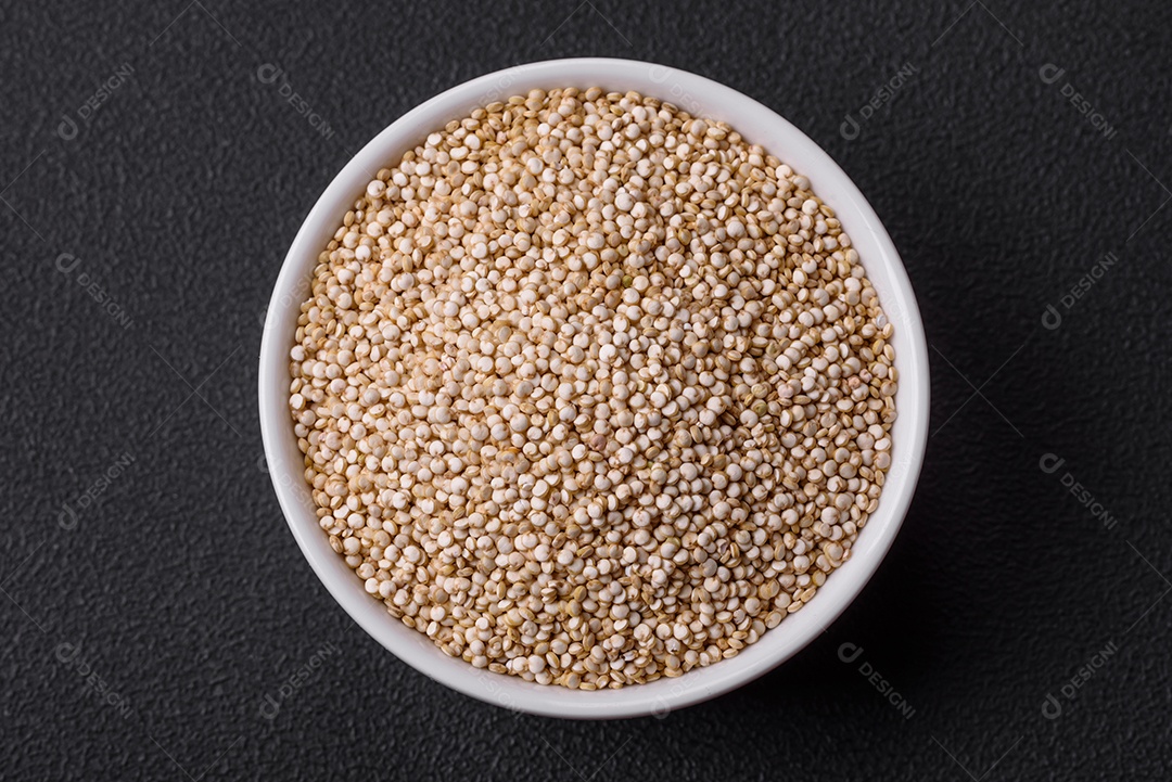 Quinoa crua saudável em uma tigela sobre um fundo escuro de concreto. Comida saudável e útil