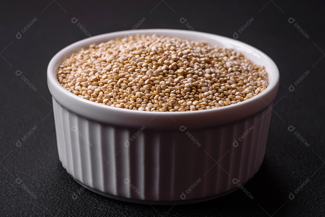 Quinoa crua saudável em uma tigela sobre um fundo escuro de concreto. Comida saudável e útil