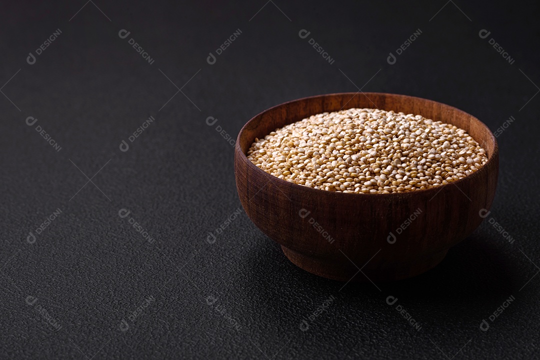 Quinoa crua saudável em uma tigela sobre um fundo escuro de concreto. Comida saudável e útil