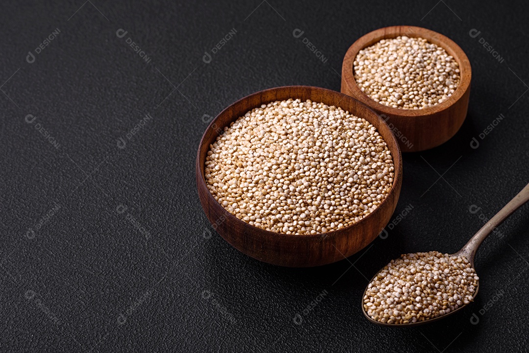 Quinoa crua saudável em uma tigela sobre um fundo escuro de concreto. Comida saudável e útil