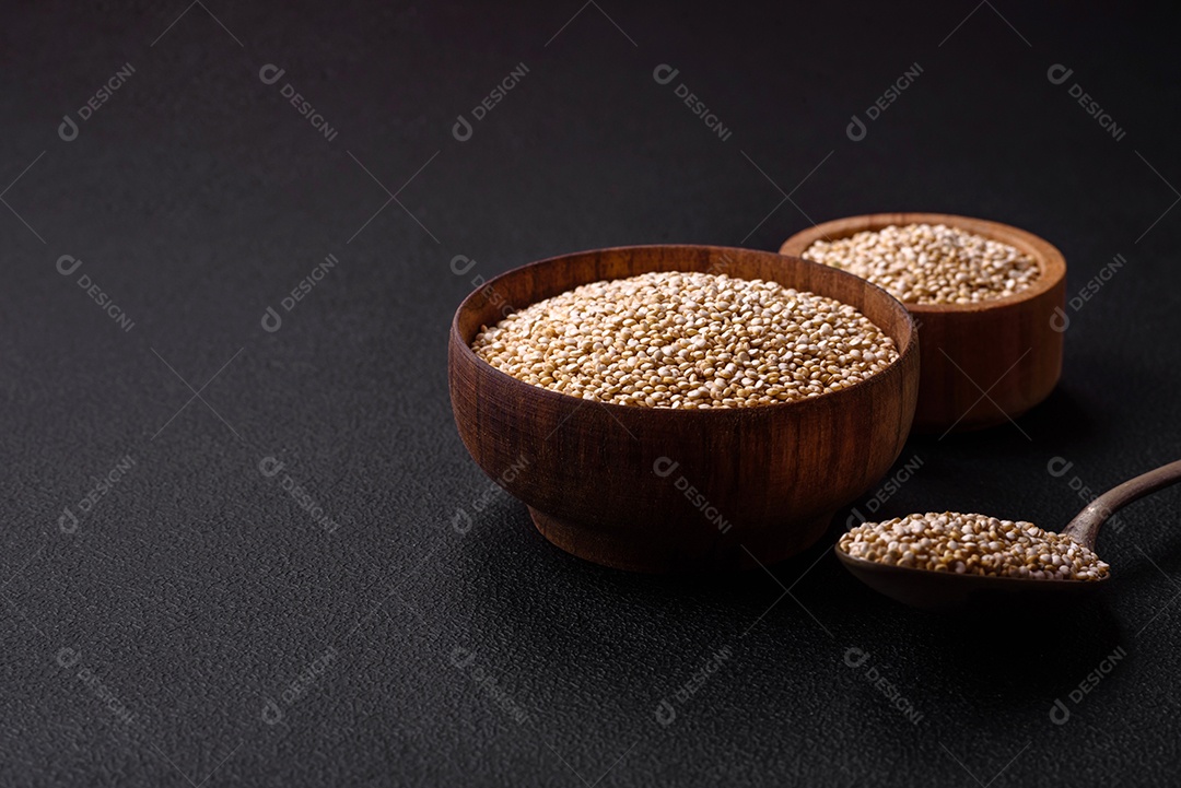 Quinoa crua saudável em uma tigela sobre um fundo escuro de concreto. Comida saudável e útil