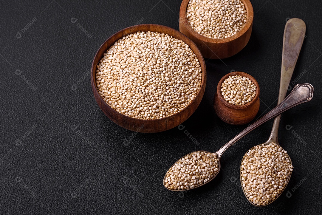 Quinoa crua saudável em uma tigela sobre um fundo escuro de concreto. Comida saudável e útil