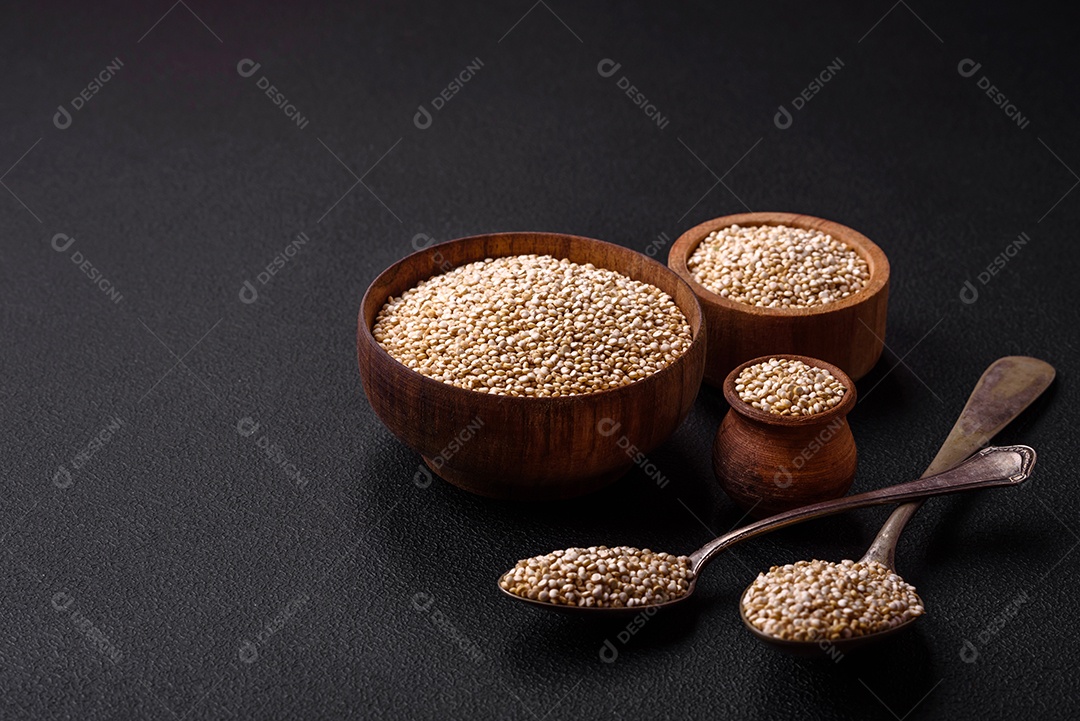 Quinoa crua saudável em uma tigela sobre um fundo escuro de concreto. Comida saudável e útil