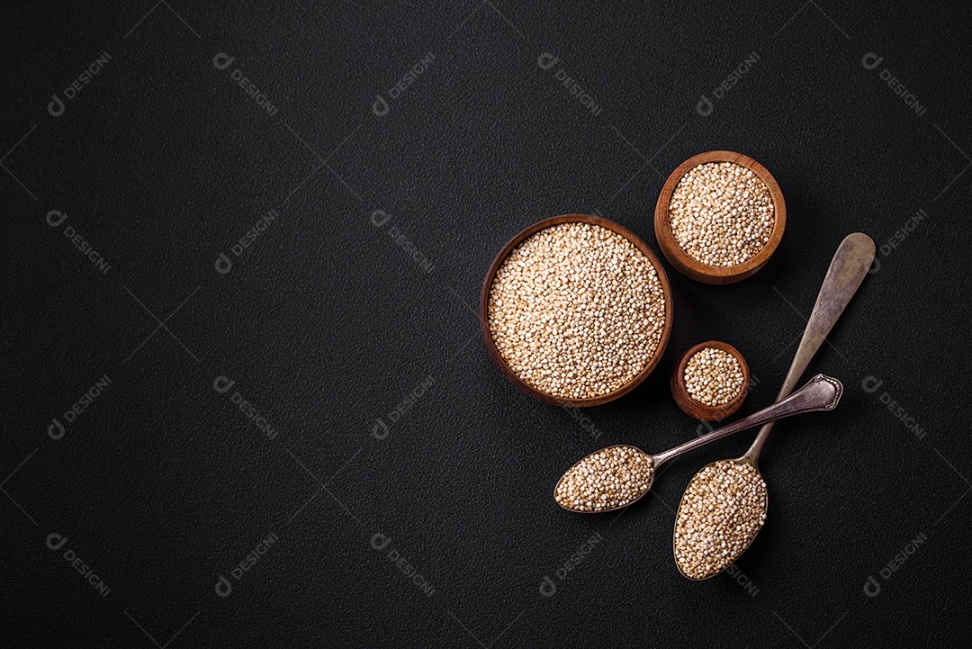 Quinoa crua saudável em uma tigela sobre um fundo escuro de concreto. Comida saudável e útil