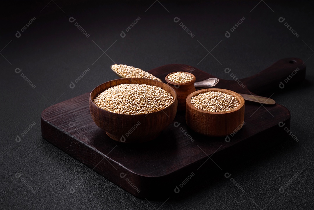 Quinoa crua saudável em uma tigela sobre um fundo escuro de concreto. Comida saudável e útil