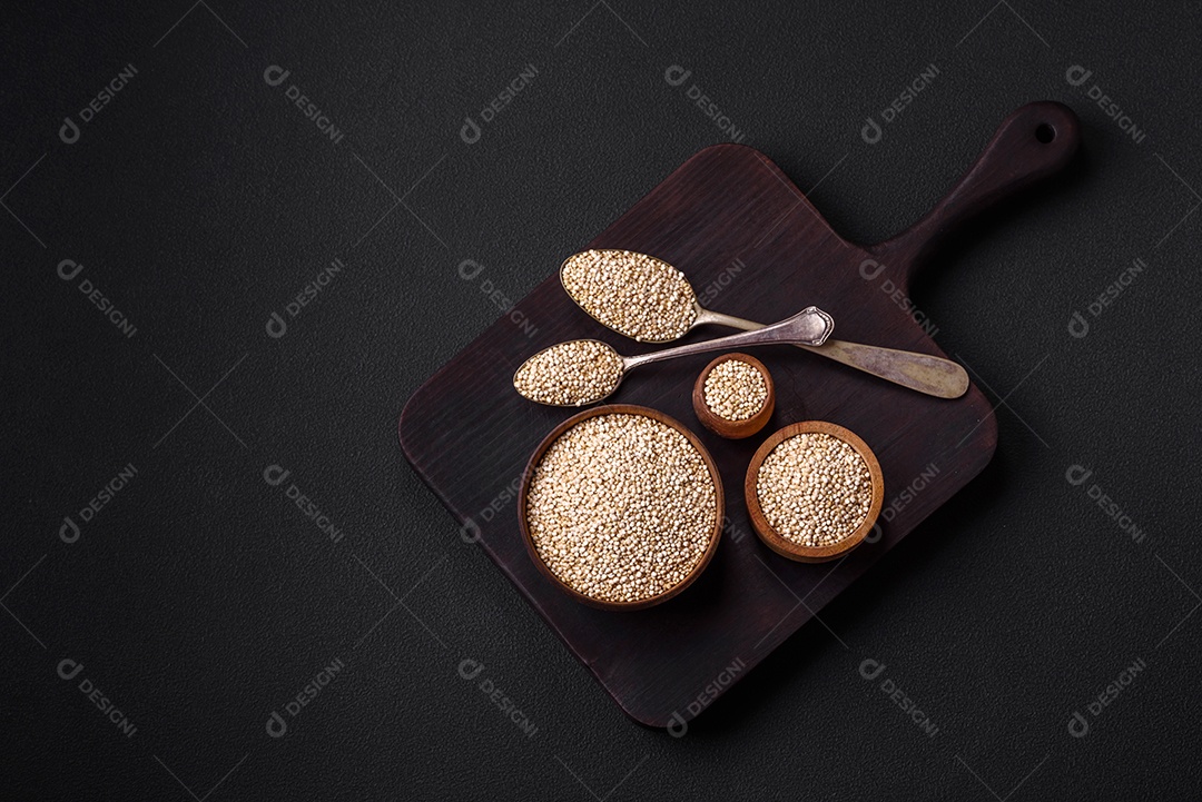 Quinoa crua saudável em uma tigela sobre um fundo escuro de concreto. Comida saudável e útil