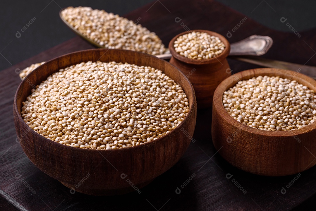 Quinoa crua saudável em uma tigela sobre um fundo escuro de concreto. Comida saudável e útil