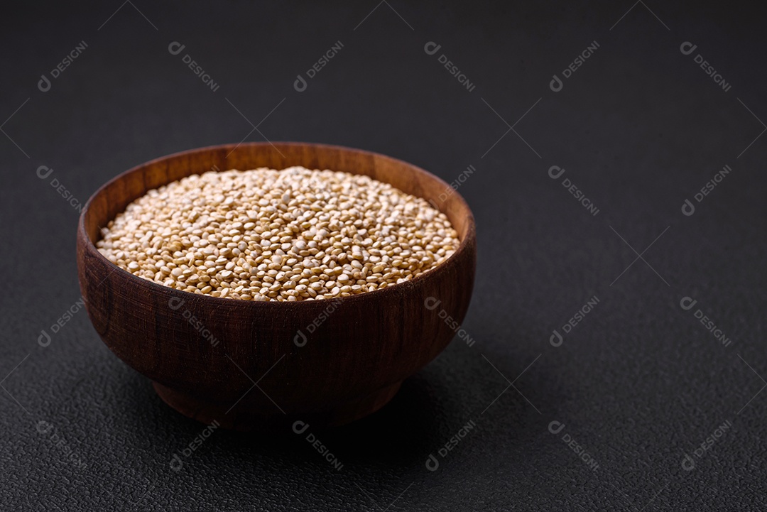 Quinoa crua saudável em uma tigela sobre um fundo escuro de concreto. Comida saudável e útil
