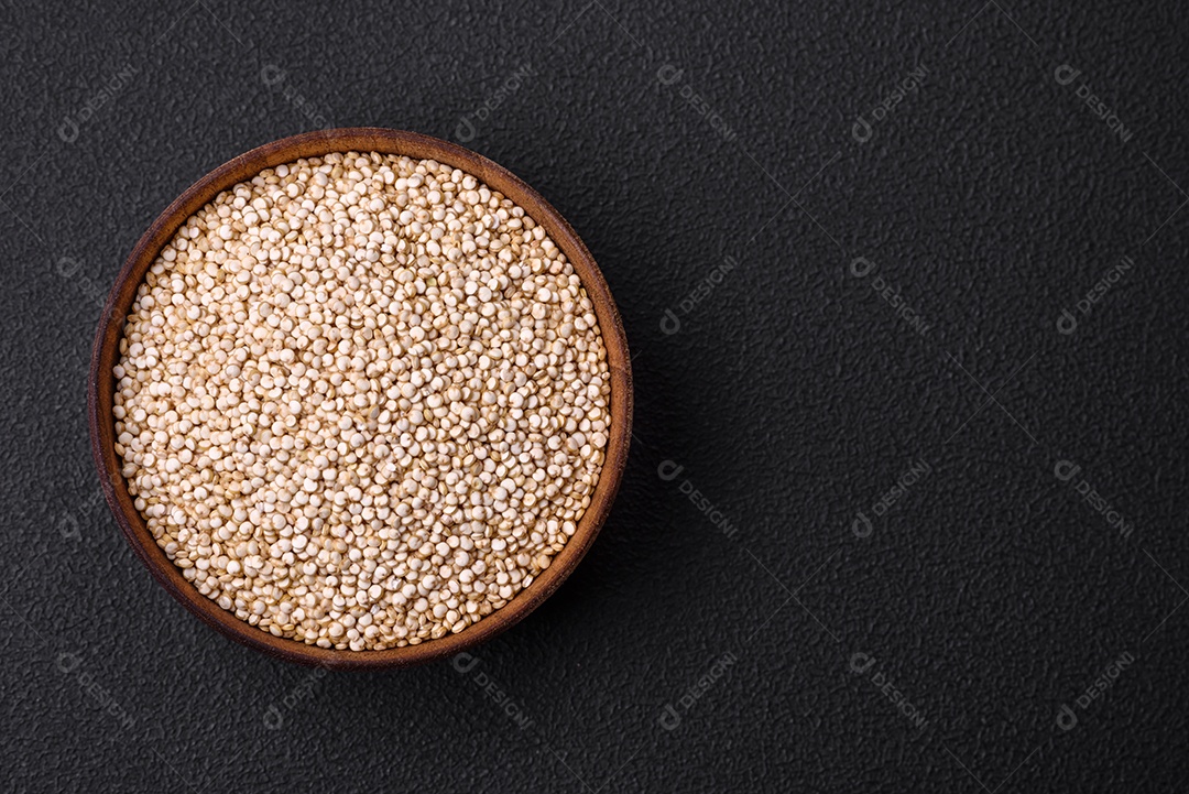 Quinoa crua saudável em uma tigela sobre um fundo escuro de concreto. Comida saudável e útil