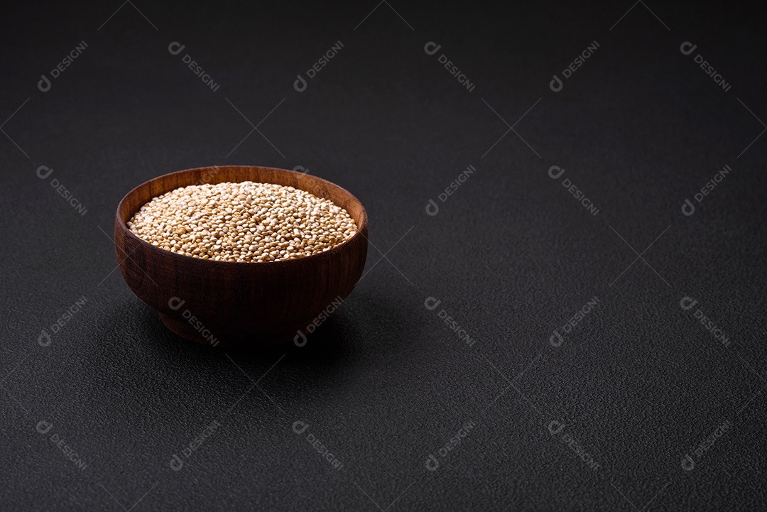Quinoa crua saudável em uma tigela sobre um fundo escuro de concreto. Comida saudável e útil